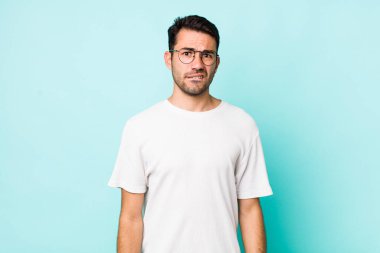 young handsome hicpanic man looking puzzled and confused, biting lip with a nervous gesture, not knowing the answer to the problem