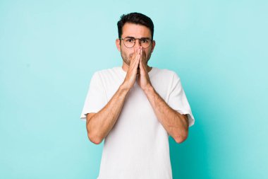 young handsome hicpanic man happy and excited, surprised and amazed covering mouth with hands, giggling with a cute expression