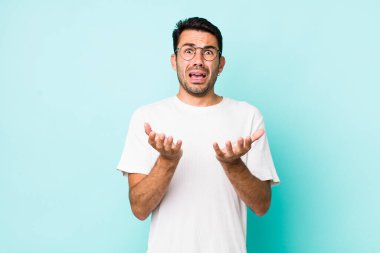 young handsome hicpanic man looking desperate and frustrated, stressed, unhappy and annoyed, shouting and screaming