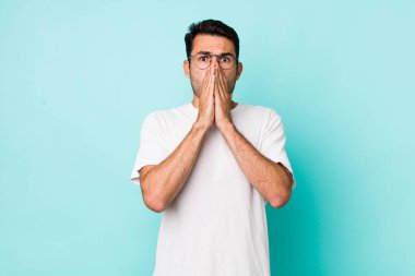 young handsome hicpanic man feeling worried, upset and scared, covering mouth with hands, looking anxious and having messed up