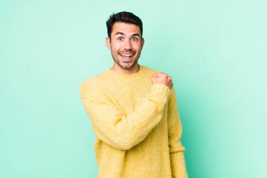 young handsome hicpanic man feeling happy, positive and successful, motivated when facing a challenge or celebrating good results