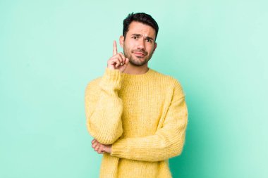 young handsome hicpanic man feeling like a genius holding finger proudly up in the air after realizing a great idea, saying eureka