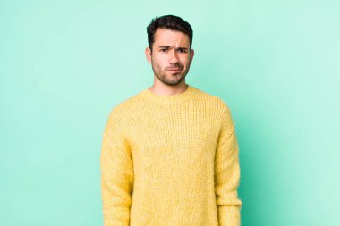 young handsome hicpanic man feeling confused and doubtful, wondering or trying to choose or make a decision