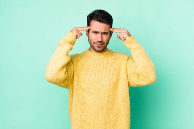 young handsome hicpanic man with a serious and concentrated look, brainstorming and thinking about a challenging problem