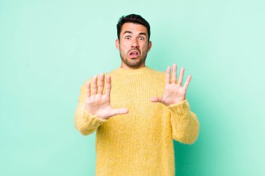 young handsome hicpanic man feeling terrified, backing off and screaming in horror and panic, reacting to a nightmare