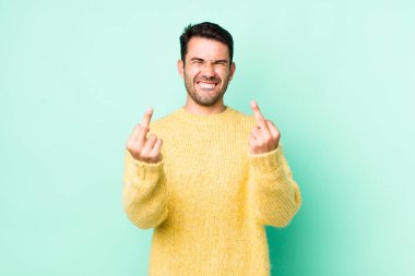 young handsome hicpanic man feeling provocative, aggressive and obscene, flipping the middle finger, with a rebellious attitude