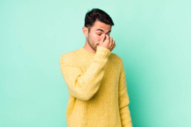 young handsome hicpanic man feeling stressed, unhappy and frustrated, touching forehead and suffering migraine of severe headache
