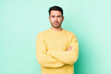 young handsome hicpanic man feeling displeased and disappointed, looking serious, annoyed and angry with crossed arms