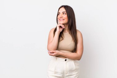 Genç ve güzel bir kadın mutlu bir şekilde gülümsüyor ve hayal kuruyor ya da şüphe ediyor.