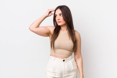 Genç, güzel bir kadın şaşkın ve kafası karışmış hissediyor, başını kaşıyor ve yan tarafa bakıyor.