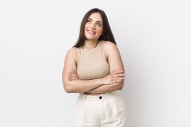 Genç, güzel bir kadın kendini mutlu, gururlu ve umutlu hissediyor, merak ediyor veya düşünüyor, çapraz kollarla boşluğu doldurmaya çalışıyor.