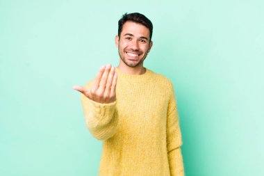 young handsome hicpanic man feeling happy, successful and confident, facing a challenge and saying bring it on! or welcoming you