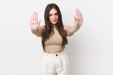 Genç ve güzel bir kadın ciddi, mutsuz, kızgın ve hoşnutsuz görünüyor. Ya da her iki avucunun içinde de dur diyor.