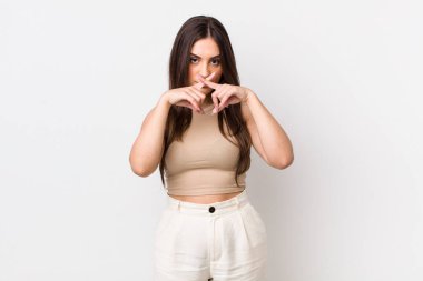 Genç ve güzel bir kadın ciddi ve hoşnutsuz görünüyor. İki parmağın önde olsun, reddedilmek için, sessizlik istiyor.