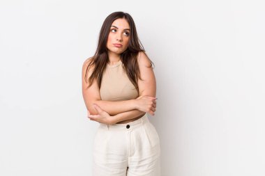 Genç, güzel bir kadın omuz silkiyor, kafası karışık ve kararsız, kolları bağlı ve şaşkın görünüyor.