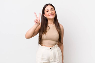 Genç, güzel bir kadın gülümsüyor ve arkadaş canlısı görünüyor. İki ya da iki numarayı gösteriyor. Elleri önde, geri sayıyor.