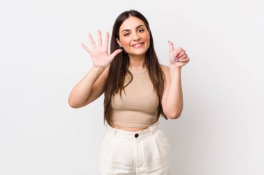 Genç, güzel bir kadın gülümsüyor ve arkadaş canlısı görünüyor. Altı ya da altıncı numarayı gösteriyor. Elleri önde, geri sayıyor.