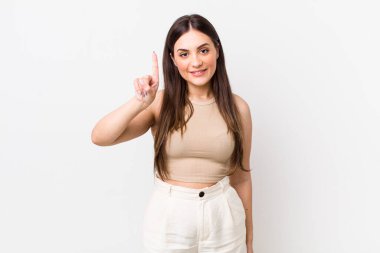 Genç ve güzel bir kadın gülümsüyor ve arkadaş canlısı görünüyor. Bir numarayı gösteriyor veya ilk eli önde, geriye doğru sayıyor.