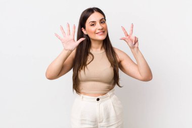 Genç, güzel bir kadın gülümsüyor ve arkadaş canlısı görünüyor. Sekiz ya da sekiz numarayı gösteriyor. Elleri önde, geri sayıyor.