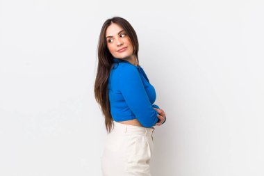 Genç, güzel bir kadın neşeyle gülümsüyor, mutlu, tatmin olmuş ve rahatlamış hissediyor, kollarını kavuşturup yan tarafa bakıyor.