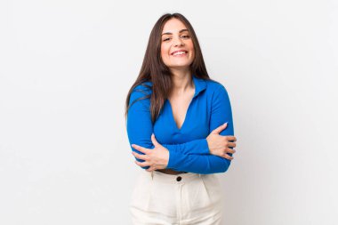 Genç ve güzel bir kadın kollarını kavuşturup mutlu bir şekilde gülüyor, rahat, pozitif ve tatmin edici bir pozla.