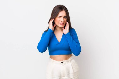 Genç, güzel bir kadın sinirli, stresli ve sinirli görünüyor, iki kulağını da sağır edici bir ses, ses ya da yüksek sesle kapatıyor.