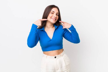 Genç, güzel bir kadın, kendine güvenerek gülümsüyor. Kendi gülüşünü gösteriyor. Olumlu, rahat, tatmin olmuş bir tavır.