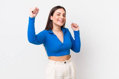 Genç ve güzel bir kadın muzaffer bir şekilde bağırıyor. Heyecanlı, mutlu ve şaşırmış görünüyor. Kutlama yapıyor.