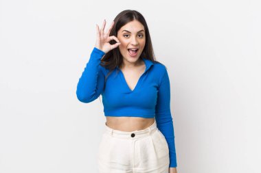 Genç ve güzel bir kadın kendini başarılı ve tatmin olmuş hissediyor, ağzı açık gülümsüyor, elle işaret veriyor.