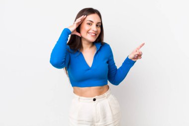 Genç, güzel bir kadın gülüyor, mutlu, pozitif ve şaşırmış görünüyor, yanal fotokopi alanını işaret eden harika bir fikri fark ediyor.