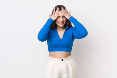 Genç ve güzel bir kadın stresli ve endişeli, depresif ve hayal kırıklığına uğramış hissediyor, iki elini de başa kaldırıyor.