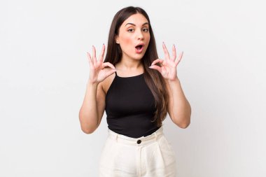 Genç, güzel bir kadın şok olmuş, şaşırmış ve şaşırmış hissediyor. İki eliyle de onay işareti yapıyor.