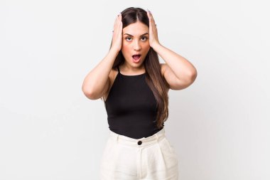 Genç ve güzel bir kadın hoş olmayan bir şekilde şok olmuş, korkmuş ya da endişeli görünüyor ağzı sonuna kadar açık ve iki kulağını da elleriyle kapatıyor.