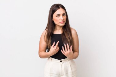 Genç ve güzel bir kadın, şaşkın ve şaşkın bir bakışla kendini işaret ediyor, seçildiğine şaşırmış ve şaşırmış.