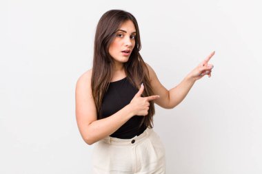 Genç, güzel bir kadın şaşkın ve şaşırmış hissediyor. Yan taraftaki fotokopi alanını işaret ediyor. Şaşırmış, ağzı açık bir bakışla.