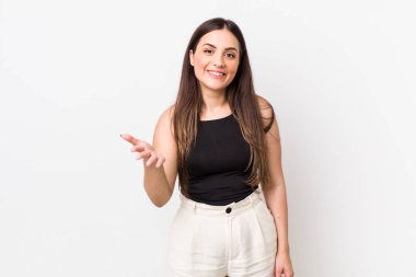 Genç, güzel bir kadın gülümsüyor, mutlu, kendinden emin ve arkadaş canlısı görünüyor, bir anlaşmaya varmak için el sıkışmayı teklif ediyor, işbirliği yapıyor.