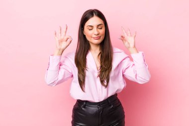 Genç ve güzel bir kadın konsantre olmuş ve meditasyon yapıyor, tatmin olmuş ve rahatlamış hissediyor, düşünüyor ya da bir seçim yapıyor.