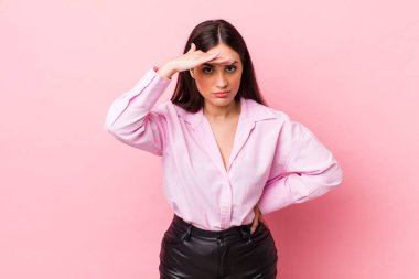 Genç, güzel bir kadın şaşkınlık ve şaşkınlık içinde bakıyor. Alnı açık, uzaklara bakıyor, izliyor ya da arıyor.