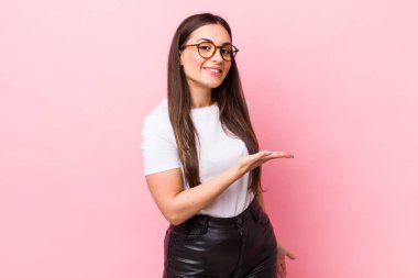 Genç, güzel bir kadın neşeyle gülümsüyor, mutlu hissediyor ve fotokopi alanında bir konsept gösteriyor.