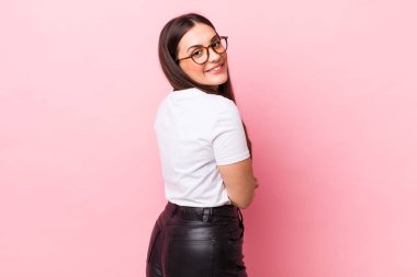 Genç, güzel bir kadın neşeyle gülümsüyor, mutlu, tatmin olmuş ve rahatlamış hissediyor, kollarını kavuşturup yan tarafa bakıyor.