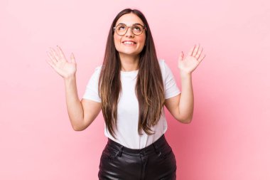 Genç, güzel bir kadın kendini mutlu, şaşkın, şanslı ve şaşırmış hissediyor. Zaferi kutlarken iki elini de havaya kaldırıyor.