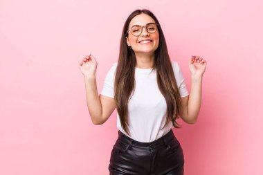 Genç ve güzel bir kadın son derece mutlu ve şaşırmış görünüyor, başarıyı kutluyor, bağırıyor ve zıplıyor.