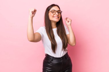 Genç ve güzel bir kadın muzaffer bir şekilde bağırıyor. Heyecanlı, mutlu ve şaşırmış görünüyor. Kutlama yapıyor.