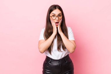 Genç ve güzel bir kadın şok olmuş ve korkmuş hissediyor, ağzı açık ve elleri yanaklarında korkmuş görünüyor.