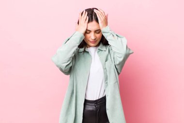 Genç ve güzel bir kadın stresli ve endişeli, depresif ve hayal kırıklığına uğramış hissediyor, iki elini de başa kaldırıyor.