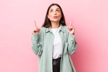 Genç ve güzel bir kadın huşu içinde ve ağzı açık bir şekilde şaşkın ve şaşkın bir bakışla yukarıya bakıyor.