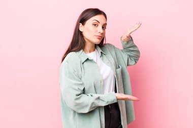 Genç ve güzel bir kadın bir objeyi iki eliyle fotokopi alanında tutuyor, bir objeyi gösteriyor, sunuyor ya da reklamını yapıyor.