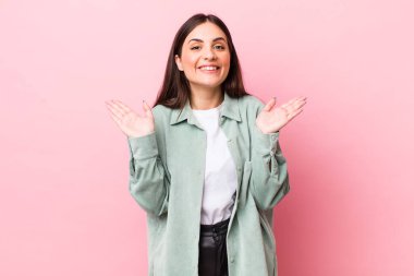 Genç, güzel bir kadın mutlu ve heyecanlı görünüyor. Beklenmedik bir sürprizle şoke olmuş. İki eli yüzü açık.