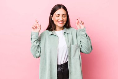 Genç, güzel bir kadın gülümsüyor ve endişeyle iki parmağını çaprazlıyor, endişeli ve iyi şanslar diliyor.