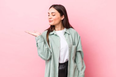 Genç, güzel bir kadın kendini mutlu hissediyor ve gülümsüyor. Yan taraftaki bir nesneye ya da konsepte bakıyor.